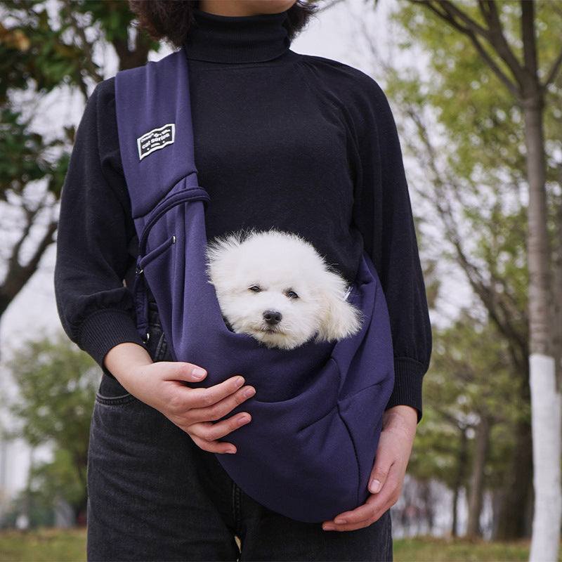 Bolsa de ombro para animais de estimação, na cor azul escuro, com um cão fofinho dentro, usada à frente do corpo.