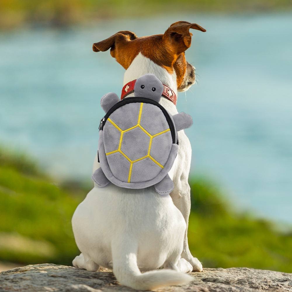 Mochila pet em formato de tartaruga, cinza com detalhes amarelos, usada por um cão de pelagem branca e marrom.