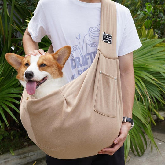 Bolsa de transporte para animais de estimação em tom bege, carregando um cão corgi, apresentando um design ergonómico e confortável.